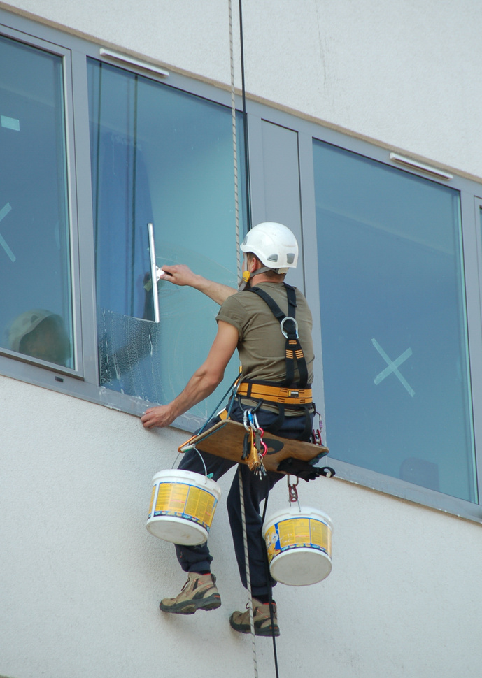 Window cleaner hanging outside building cleaning