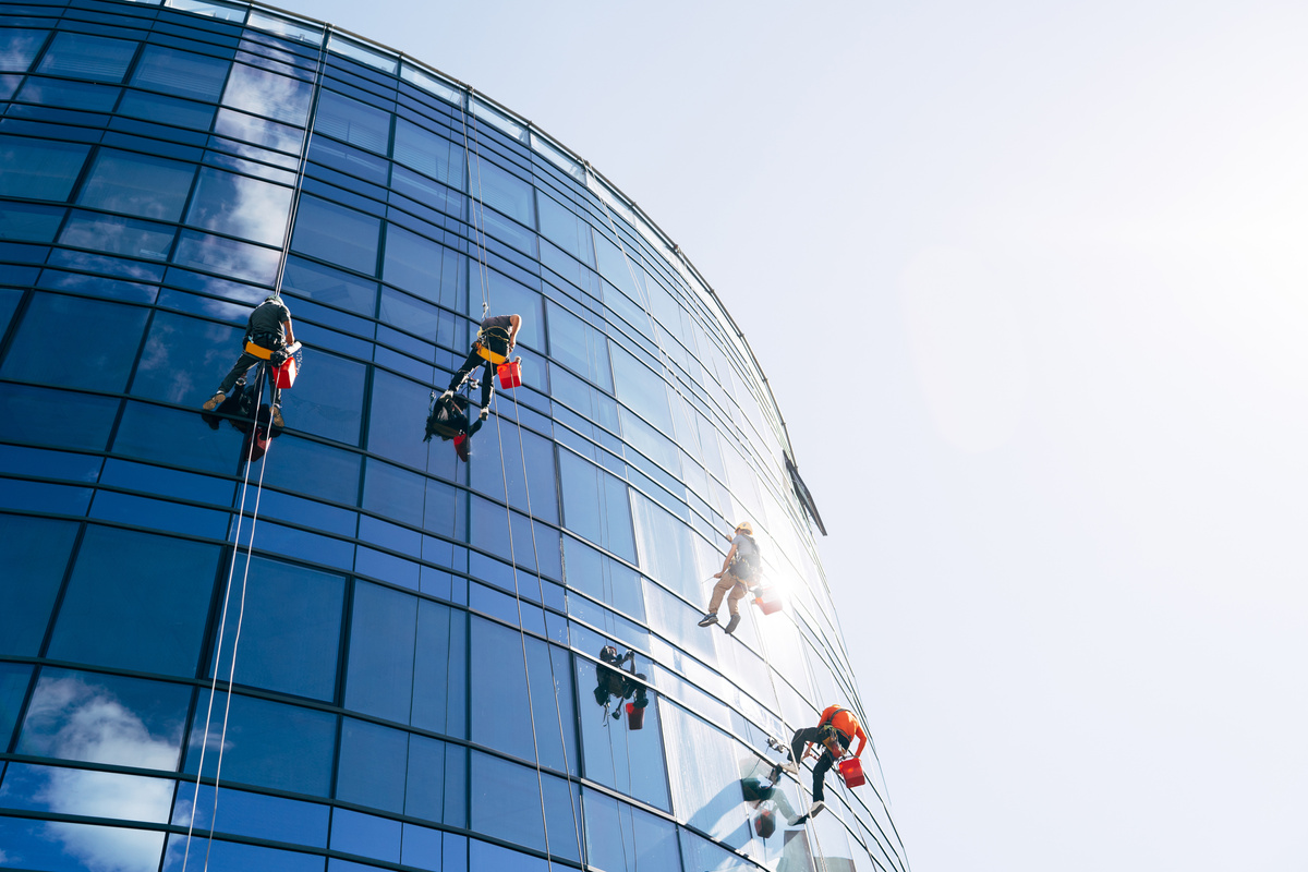 Industrial Climbers Cleaning Blue Windows outside Building.